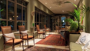 A spacious room with large windows, a central rug, and several seating areas. - Pousada Villa do Conde (Brotas)