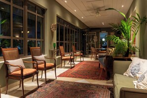 A spacious room with large windows, a central rug, and several seating areas. - Pousada Villa do Conde (Brotas)