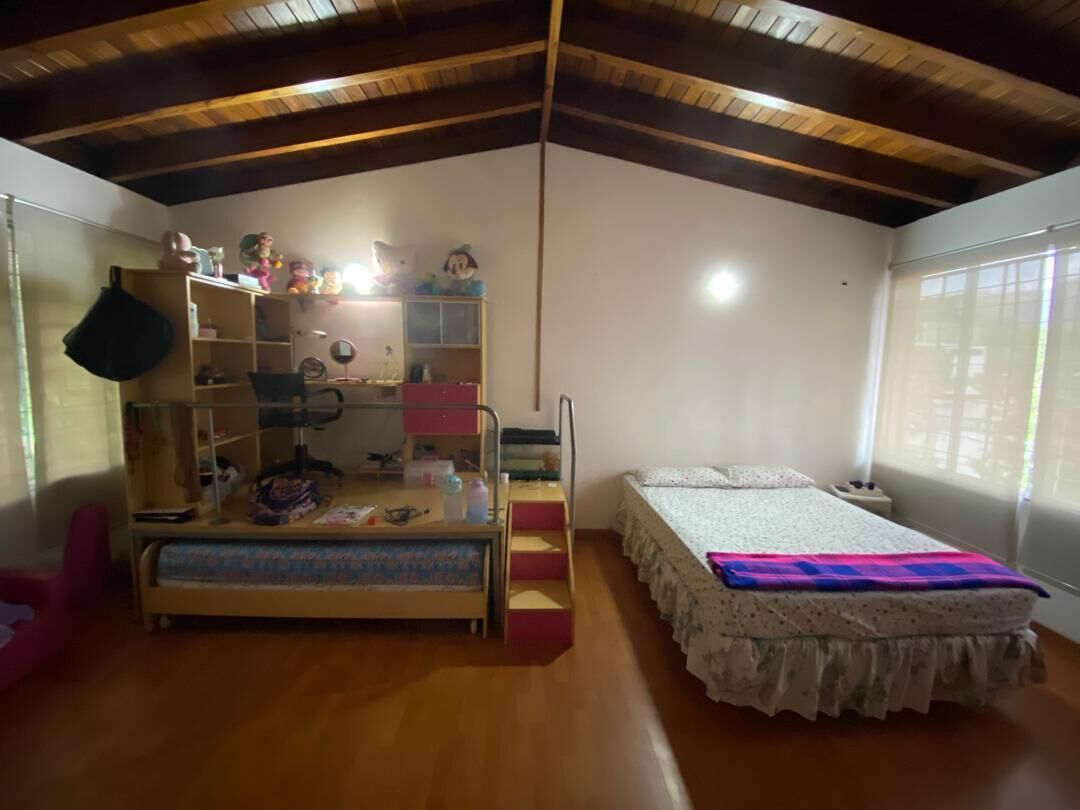 A room with a bunk bed, a desk, a chair, a bookshelf, and a window.