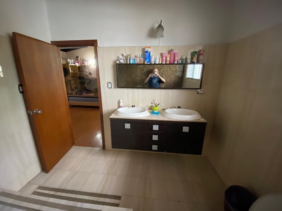 A bathroom with two sinks, a mirror, and a shelf with toiletries.