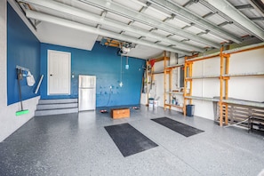 A clean, well-lit garage with a blue wall, a white door, and a workbench area. - Coastal Modern Home | Walk To Beach, Food & Shopping (Marco Island)