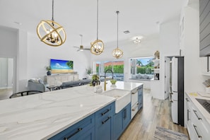 A modern kitchen with a large island, blue cabinets, and pendant lighting. - Coastal Modern Home | Walk To Beach, Food & Shopping (Marco Island)
