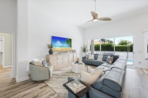 Un salon spacieux avec un grand canapé, une table basse et un téléviseur posé sur un meuble en bois.