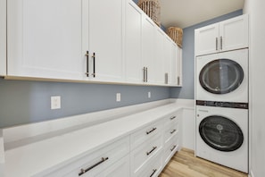 A laundry room with white cabinets, a washing machine, and a dryer. - Coastal Modern Home | Walk To Beach, Food & Shopping (Marco Island)