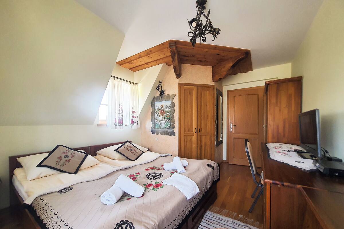 Un dormitorio con cama, un escritorio con silla, televisor y techo de madera.