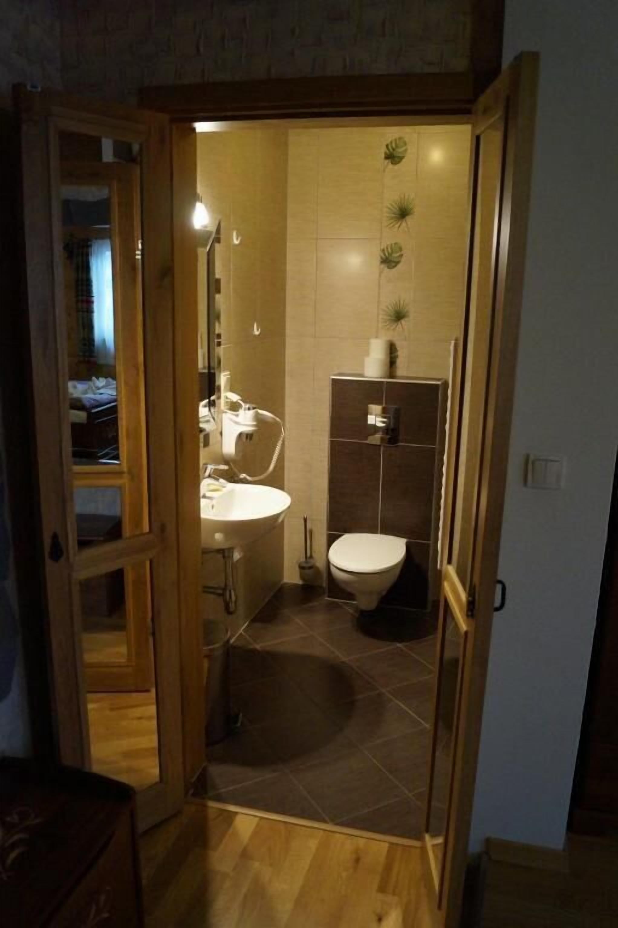 A small, narrow bathroom with a toilet, sink, and shower area.