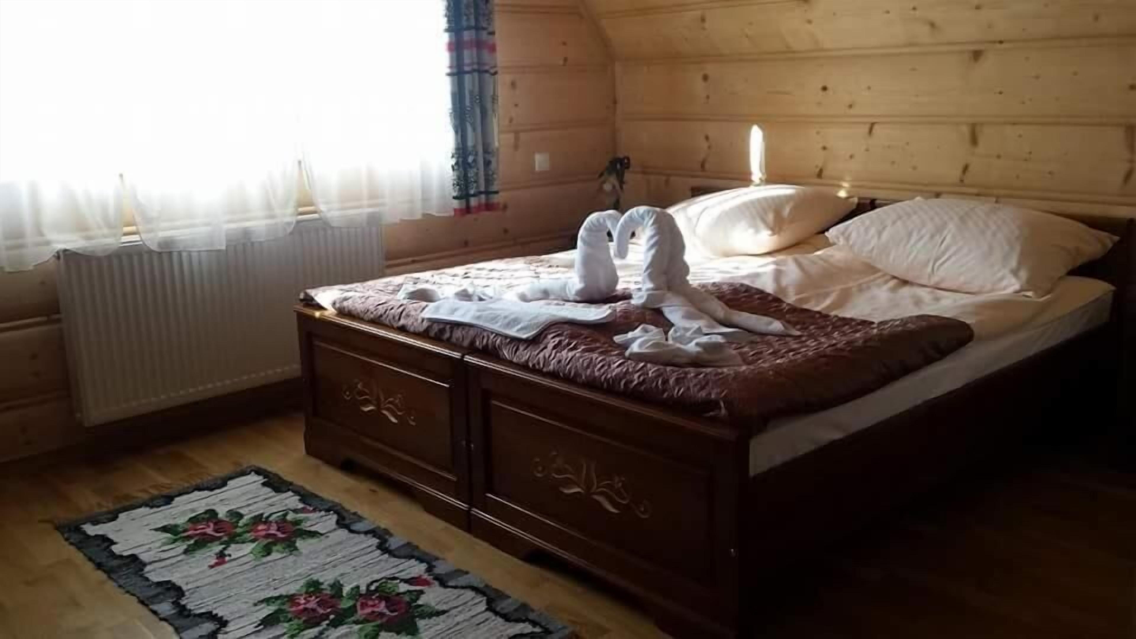 A wooden room with a bed, a radiator, and a floral rug.