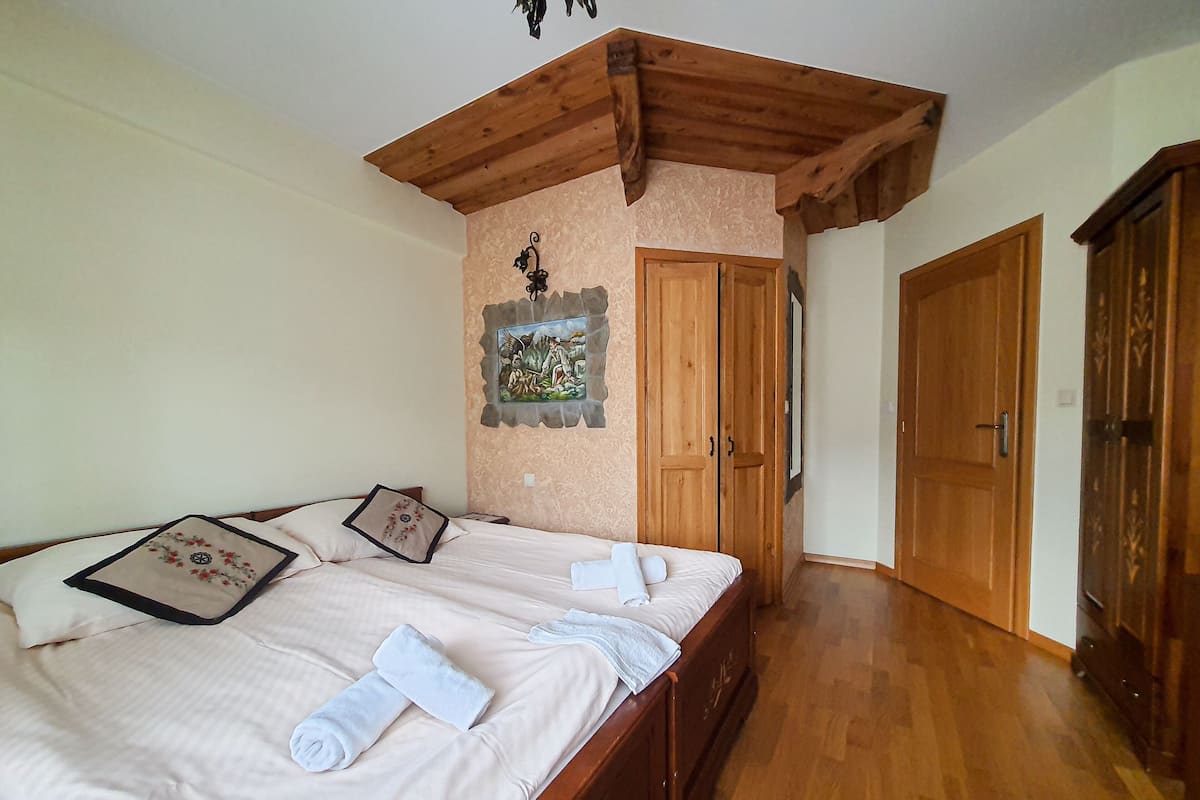 Un dormitorio con una cama de madera, un cuadro en la pared y un armario de madera.