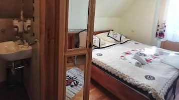 Un dormitorio con cama de madera, mesita de noche, espejo y ventana con cortinas.