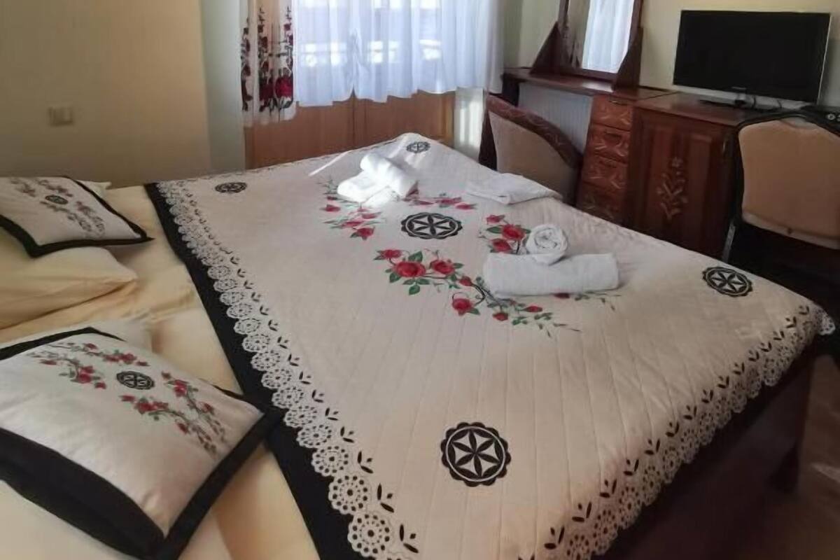Un dormitorio con cama, escritorio, silla, televisor y candelabro.