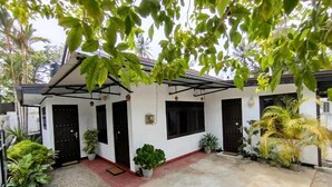 A white building with a covered porch, potted plants, and a concrete patio. - Step Inn Ahangama  (Ahangama)