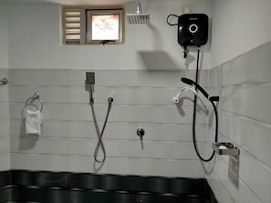A bathroom with a shower, a towel rack, and a wall-mounted heater.