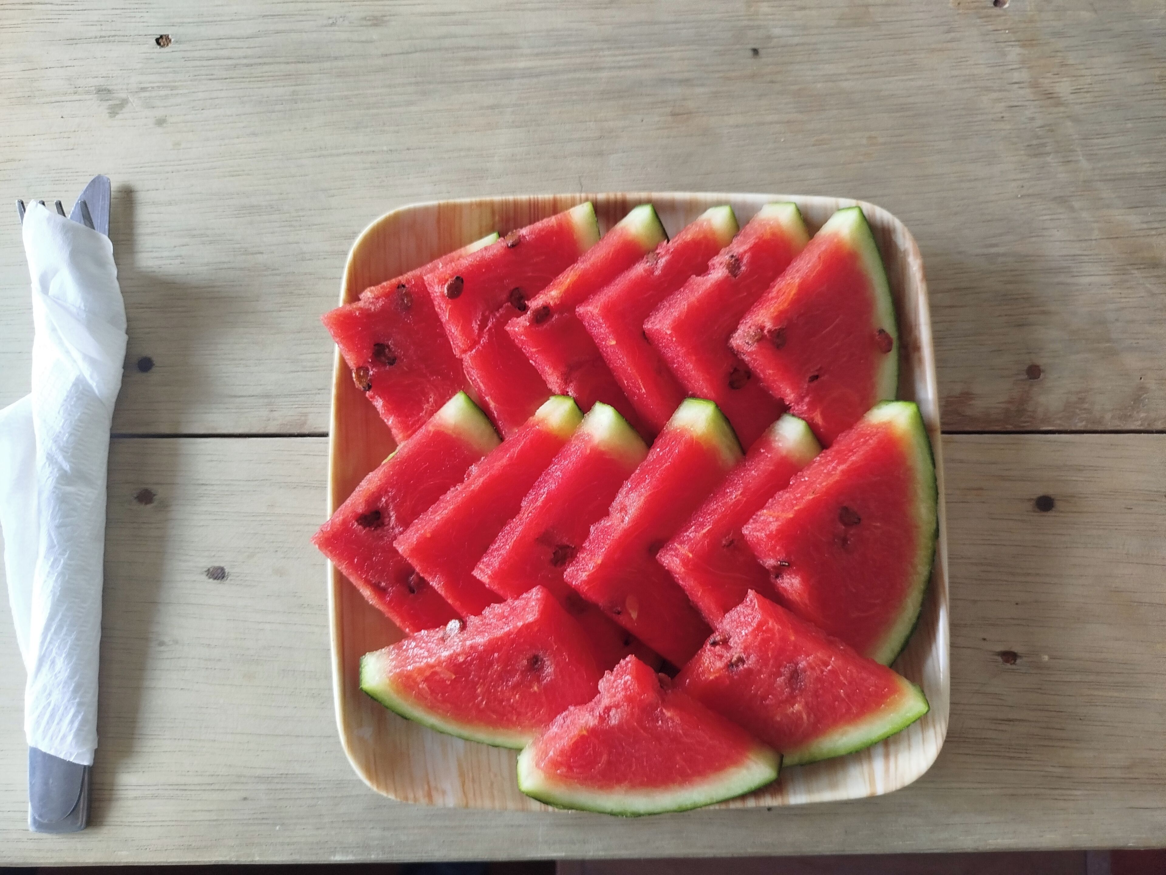 A wooden table with a plate of watermelon slices.