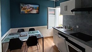 Cocina compacta con comedor, ventilador de techo y un cuadro en la pared.
