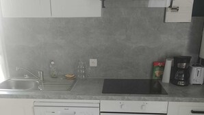Una cocina equipada con lavavajillas, horno, fregadero y cafetera.