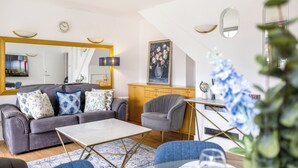 En moderne stue med sofa, lænestol, sofabord og et stort spejl.