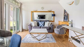 En moderne stue med en grå sofa, et sofabord og et spiseområde med et hvidt bord og stole.