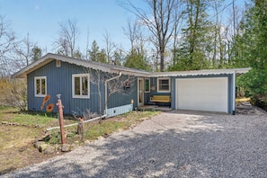 A house with a garage, a porch with a bench, and a gravel driveway.