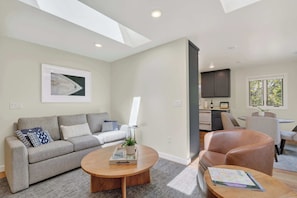 A modern living room with a grey sofa, a wooden coffee table, and a leather armchair.