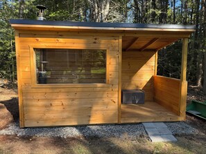 Een houten vakantiehuisje met een groot raam, een schoorsteen en een klein terras.