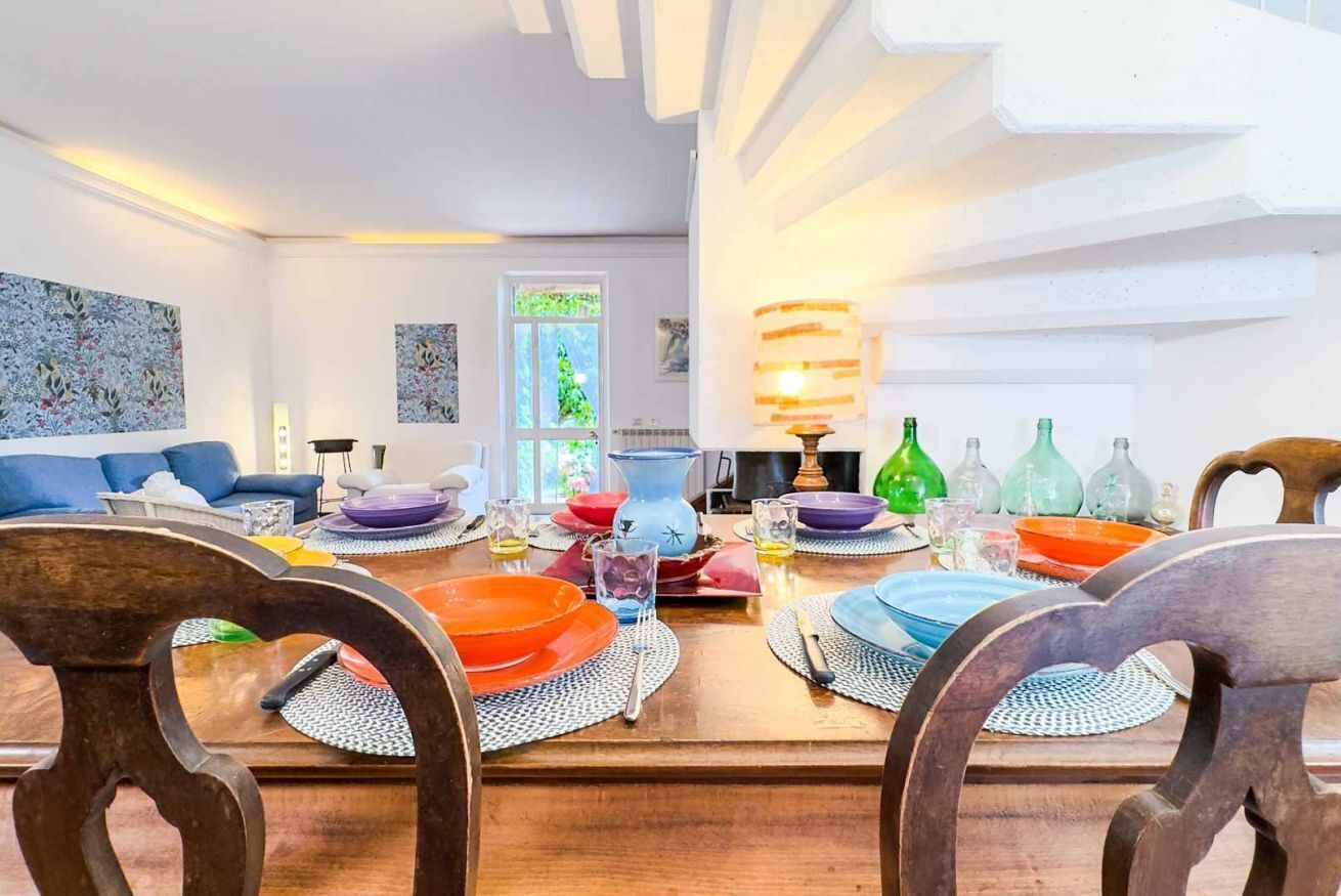 A dining area with a wooden table set for a meal, surrounded by chairs.