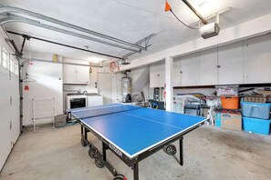 A ping pong table in a spacious, industrial-style room with metal beams, white walls, and storage cabinets. - 25% Off Oct 22-25, Steps To Sand, Roof-Top Deck! (Oxnard)