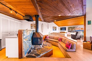 A modern living room with a stone fireplace, wooden ceiling, and a cozy seating area. - Oceanfront Retreat, Amazing Ocean Views W/Jacuzzi! (Ventura)