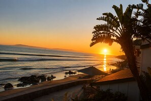 A beach scene with a sunset, ocean waves, and a person with a surfboard. - Oceanfront Retreat, Amazing Ocean Views W/Jacuzzi! (Ventura)