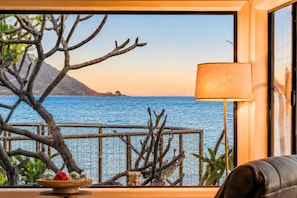 A room with a view of the sea, a lamp, and a table with decorative items. - Oceanfront Retreat, Amazing Ocean Views W/Jacuzzi! (Ventura)