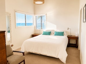 A bedroom with a bed, two bedside tables, a chair, a mirror, and two windows with blinds. - 20% Off Sept! Water Front, Perfect For Families* (Ventura)
