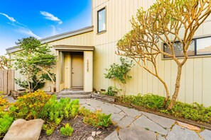 A building with a door labeled 'Lancaster' and a small garden with various plants and a tree. - Oceanfront Retreat, Amazing Ocean Views W/Jacuzzi! (Ventura)