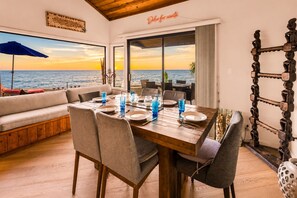 A dining area with a wooden table set for four, overlooking a scenic ocean view.