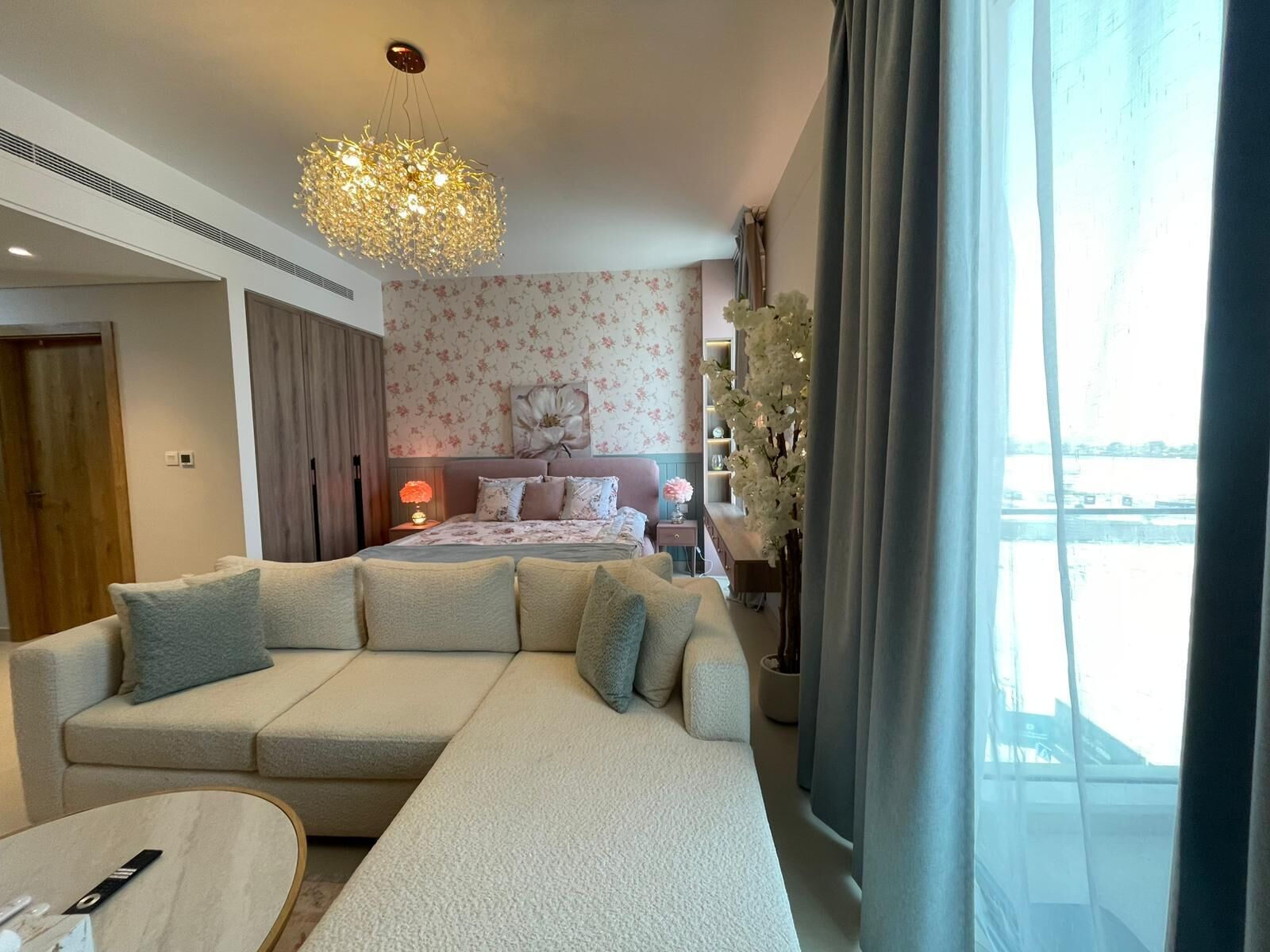 Een moderne slaapkamer met een groot bed, een sofa, een nachtkastje, een lamp en uitzicht op de omgeving.
