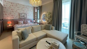 A modern bedroom with a large bed, a sofa, a round coffee table, and a view of the outdoors. - Stylish Studio Apartment with Kitchen, TV Lounge & Dining Space (Muḥāfaẓat al-Muḥarraq)