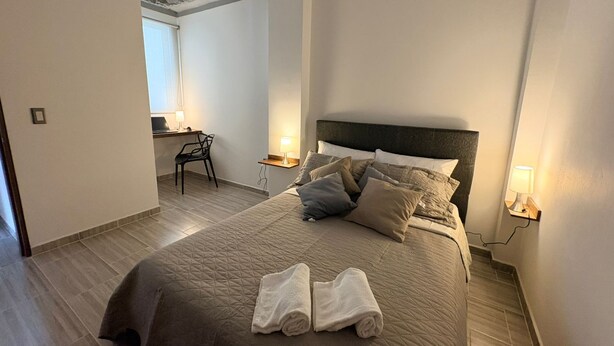 A bedroom with a bed, two bedside lamps, a chair, and a desk with a lamp. - GUADUAS, CLOSE TO THE HISTORICAL CENTER, PET FRIENDLY, APARTMENT2H+2B,WIFI -PARKING (Guaduas)