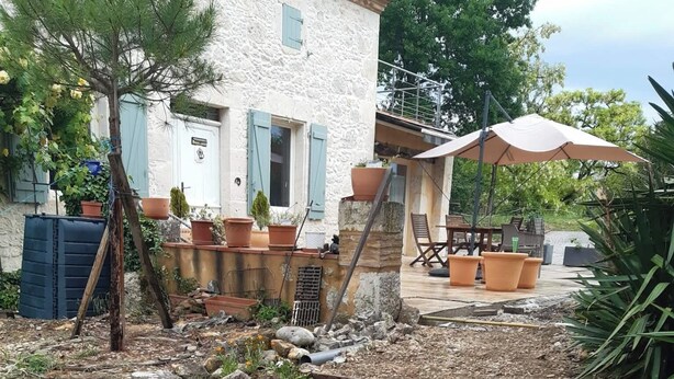 Ein Garten mit erhöhten Beeten, einer Holzbank und Kübelpflanzen.