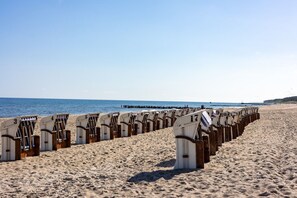 Ein Strand mit mehreren Reihen nummerierter Liegen und Sonnenschirmen.