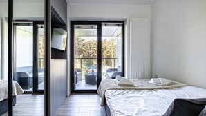 A modern hotel room with a large bed, a balcony with outdoor seating, and a view of trees and a car. - Maris | Shellter Rogowo | Balkon z widokiem na las | Blisko plaży (Rogowo)