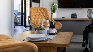 A dining area with a wooden table, a bottle of wine, glasses, and a potted plant. - Maris | Shellter Rogowo | Balkon z widokiem na las | Blisko plaży (Rogowo)