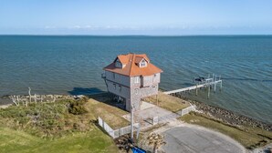 Ett hus vid kusten med ett torn, en brygga och fri utsikt över havet.