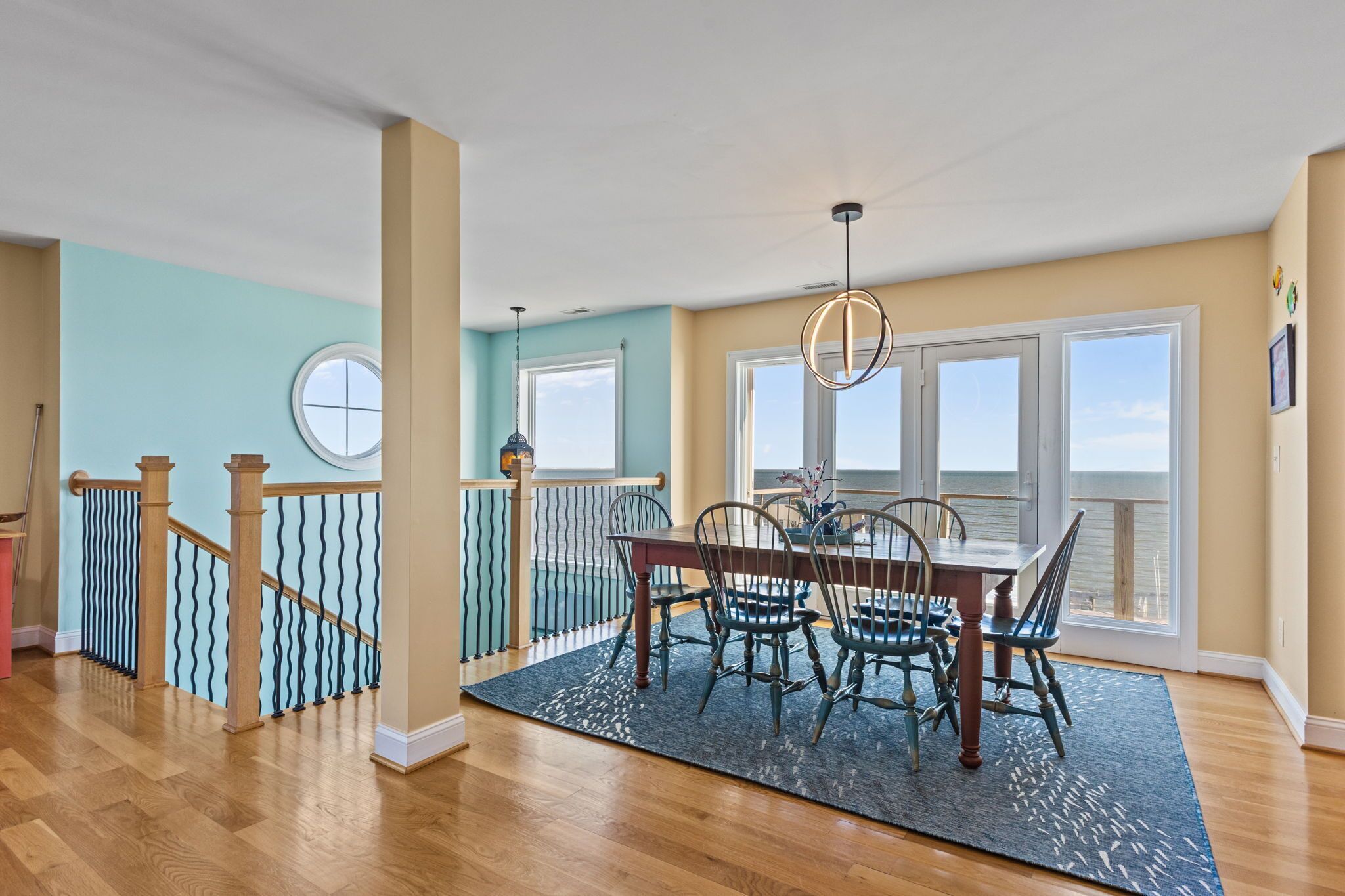 A dining area with a table and chairs, a chandelier, and large windows with a view.