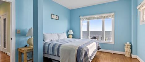 A bedroom with a bed, a window with a view, a bedside table with a lamp, and a small statue.