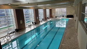 Ein Hallenbad mit freiem Blick nach außen, einem gefliesten Boden und einer Sitzgelegenheit.