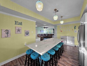 A kitchen with a marble island, bar stools, and a refrigerator. - Beach Retreat: 3  BR, 2  BA House in Crystal Beach, Sleeps 12 (Crystal Beach)