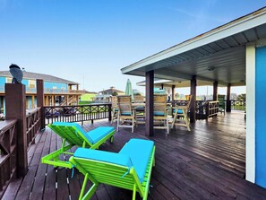 A wooden deck with green lounge chairs and a covered seating area. - Beach Retreat: 3  BR, 2  BA House in Crystal Beach, Sleeps 12 (Crystal Beach)