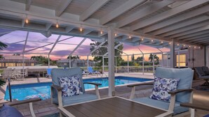 Zona junto a la piscina con sillones de descanso y vista al agua.