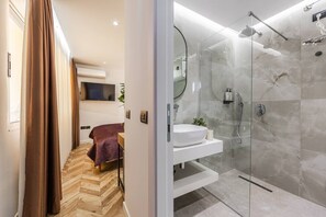 Ein modernes Badezimmer mit Duschkabine aus Glas, einem weißen Waschbecken und Holzboden.