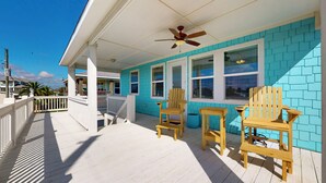 A wooden deck with a ceiling fan, two wooden chairs, and a small table. - Candy's Cove: 2  BR, 1  BA House in Crystal Beach, Sleeps 8 (Crystal Beach)