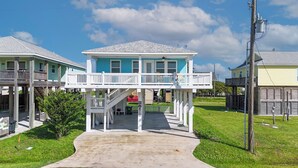 A two-story house with a balcony, a covered porch, and a front yard. - Candy's Cove: 2  BR, 1  BA House in Crystal Beach, Sleeps 8 (Crystal Beach)