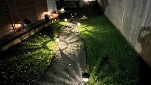Un sendero iluminado que lleva a una casa por la noche.
